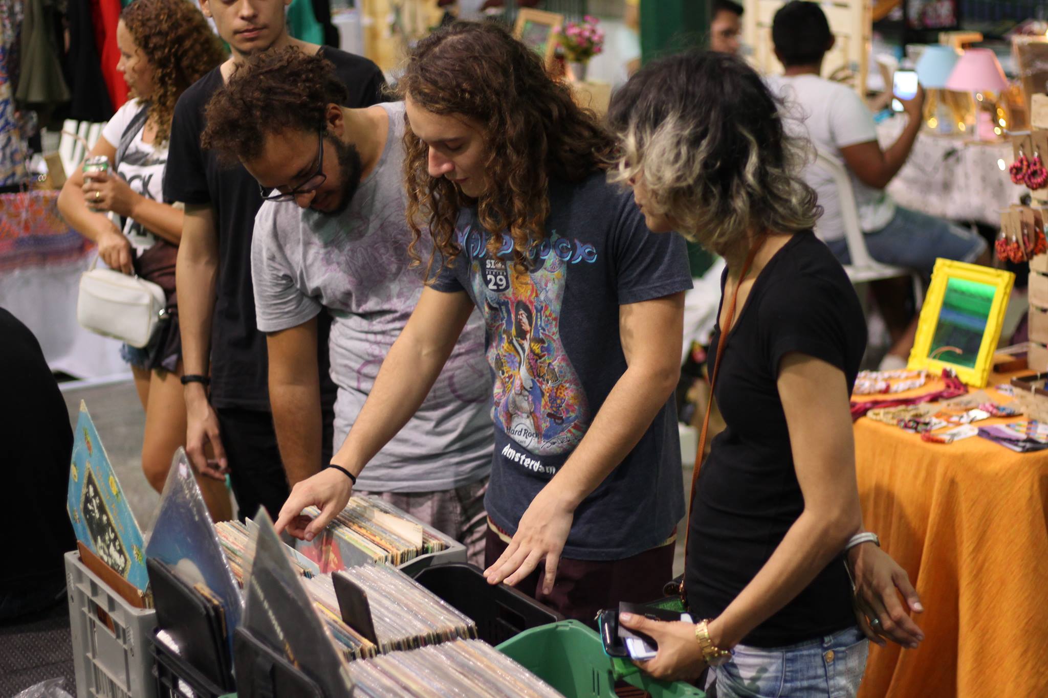 pessoas olham para uma caixa cheia de discos de vinil